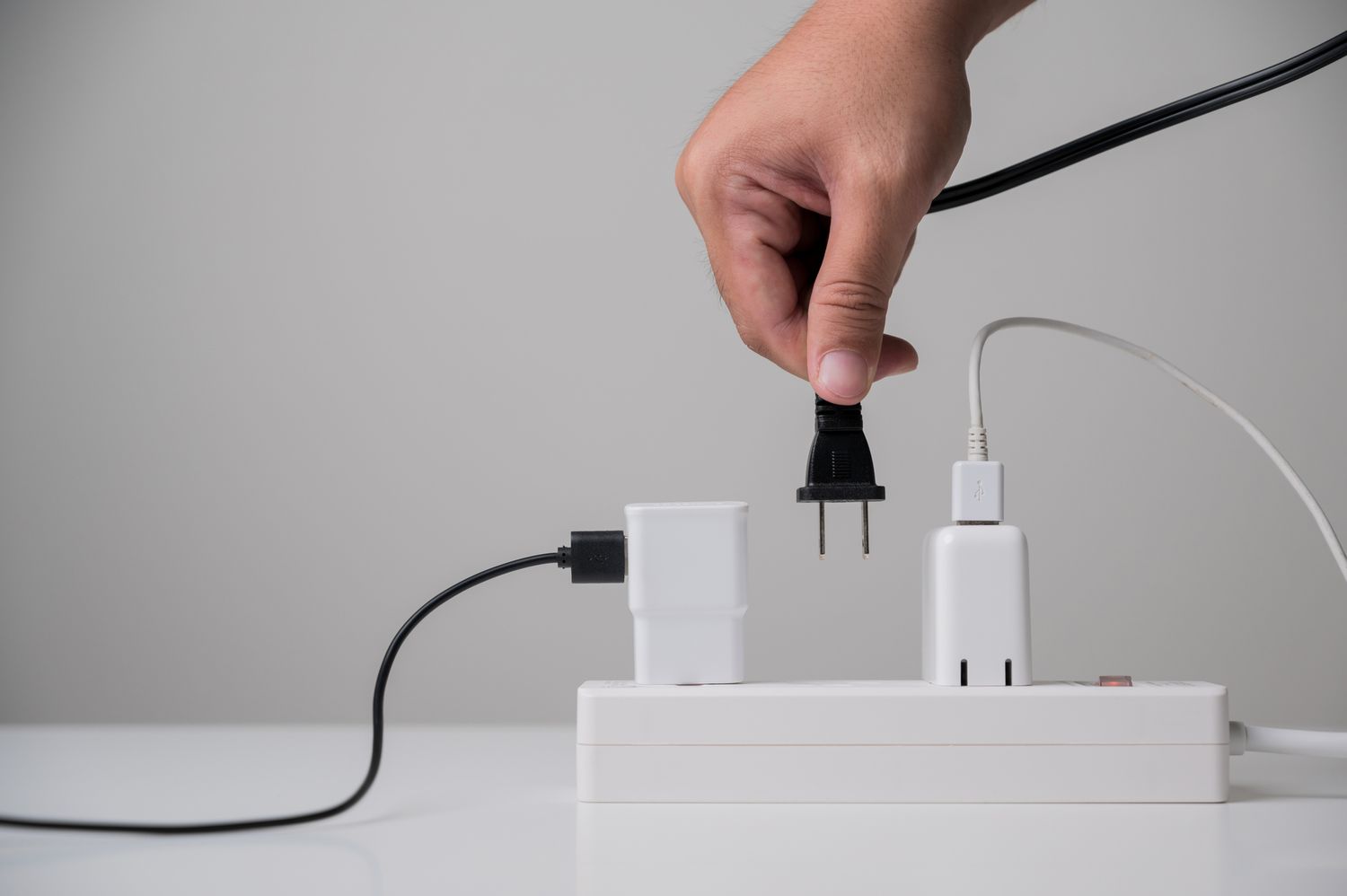 Wie man TV -Kabel richtig verbergen, müssen Sie sie nie wieder sehen 8 Person, die ein Kabel in einen Stromstreifen steckt
