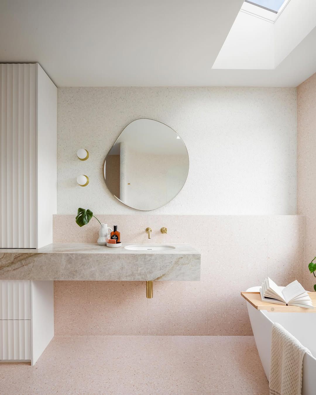 Pinkes Badezimmer mit abgerundeter welliger Spiegel und Lichtern