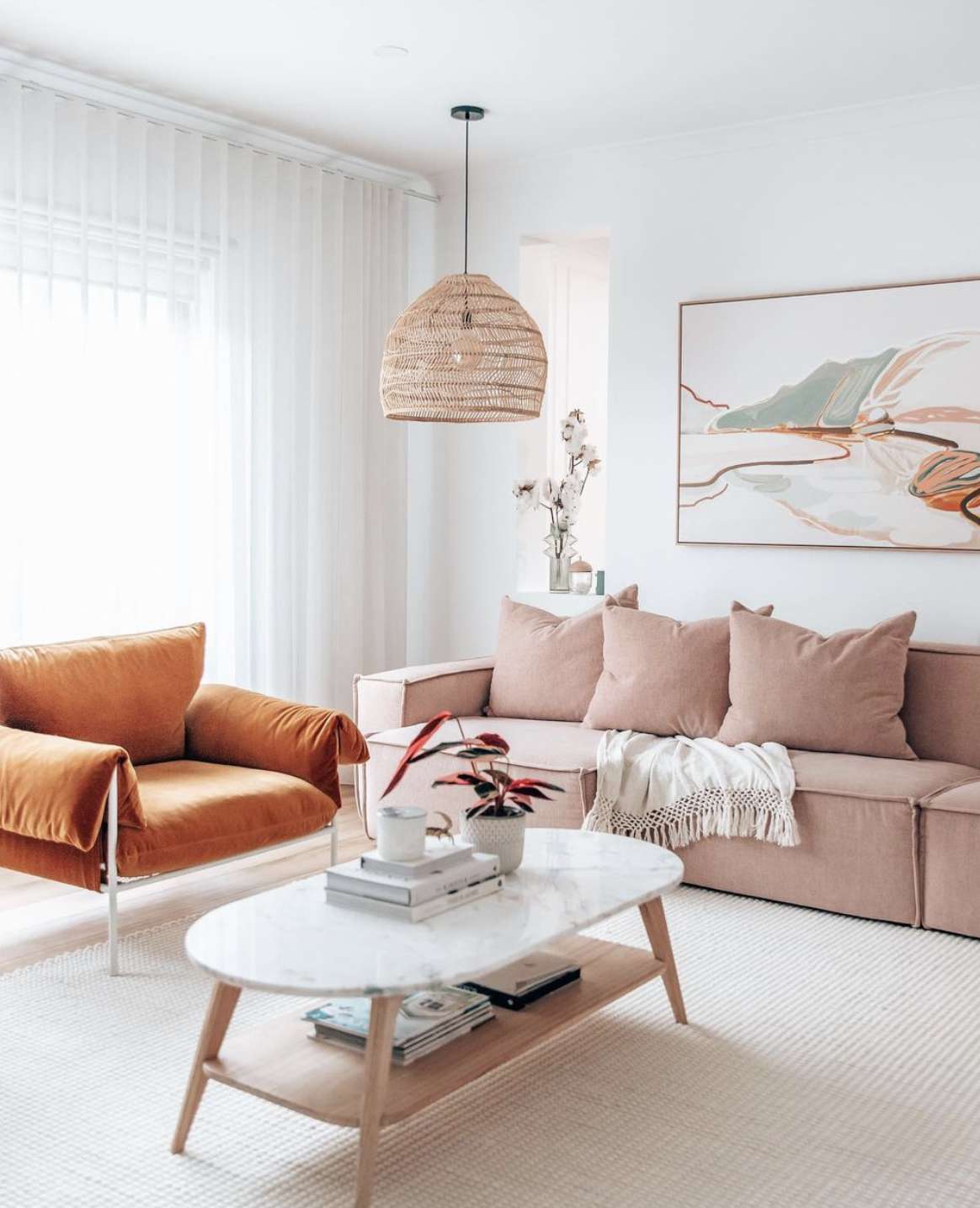 Scandi Wohnzimmer mit rosa Couch und orangefarbenem Akzentstuhl