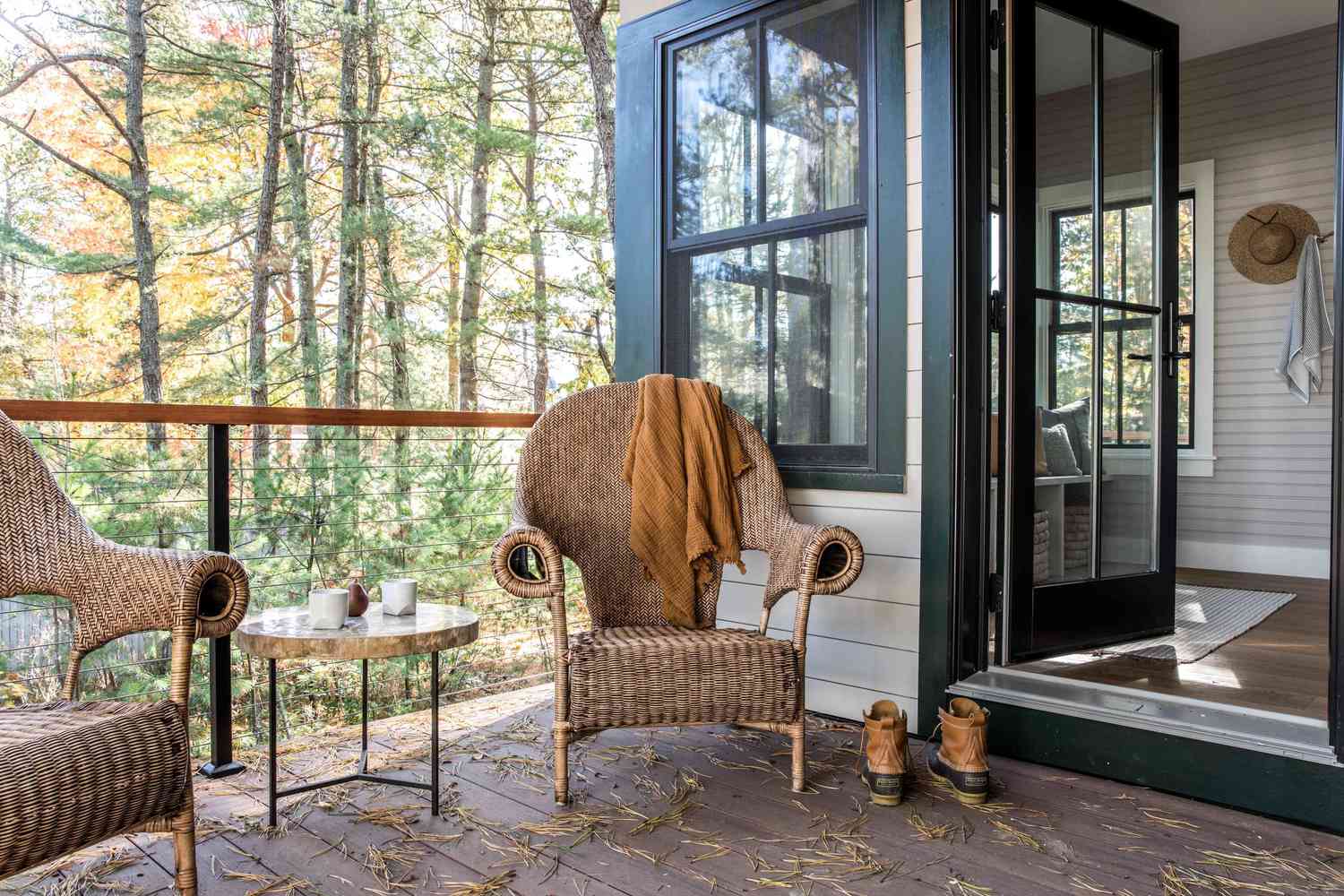 Ein Outdoor -Deck mit einem Frühstücks -Nook -Handwerk aus einem kleinen Tisch und zwei gewebten Stühlen