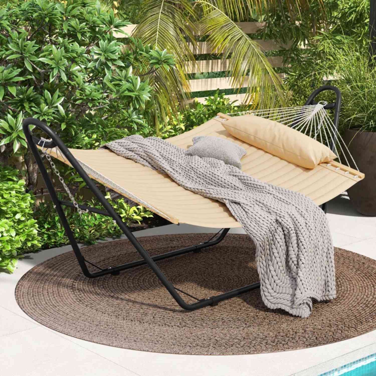 12 unserer beliebtesten Outdoor -Möbelstücke von Wayfair, alle unter 150 US -Dollar 22 Eine buttergelbe Hängematte in einem üppigen grünen Garten neben einem Pool