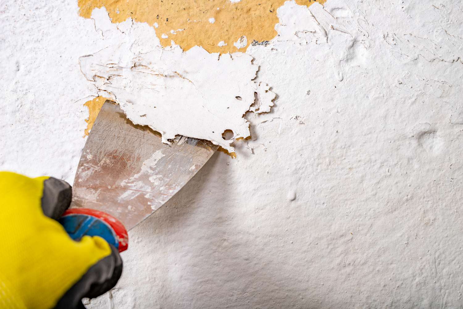 Nahaufnahme der Person, die Farbe von einer Betonoberfläche entfernt