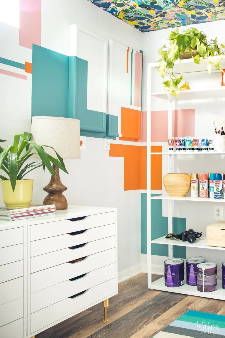 7 einfache Tricks, um unansehnliche Elektropaneele sofort zu vertuschen 8 Ein Bastelraum mit einer geometrischen blaugrünen, orangefarbenen und rosa Wandbildung, die die elektrische Platte umgibt