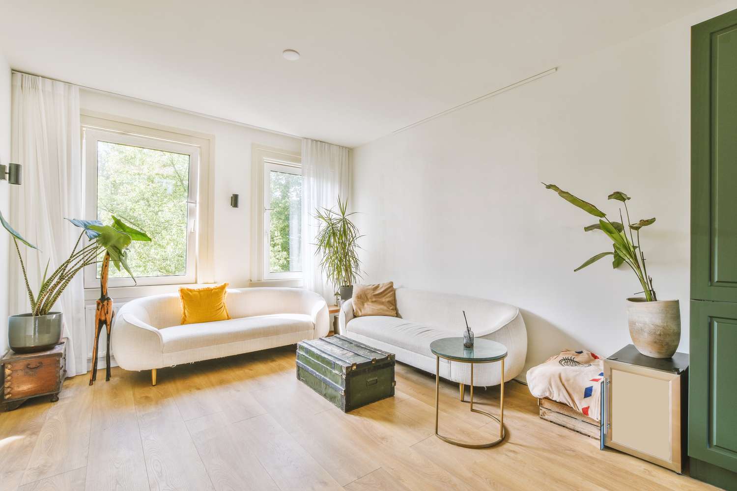 5 Häufige Dekorfehler, die Ihr Zuhause nach Ansicht von Designer weniger einladend fühlen können 6 Ein gemütliches Wohnzimmer mit Innenpflanzen und mehreren weichen Sofas mit einem Tisch in Form einer Holzkiste