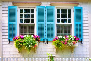 Ein Doppelfenster ist mit blauen Fensterläden auf einem Haus im Haus dekoriert