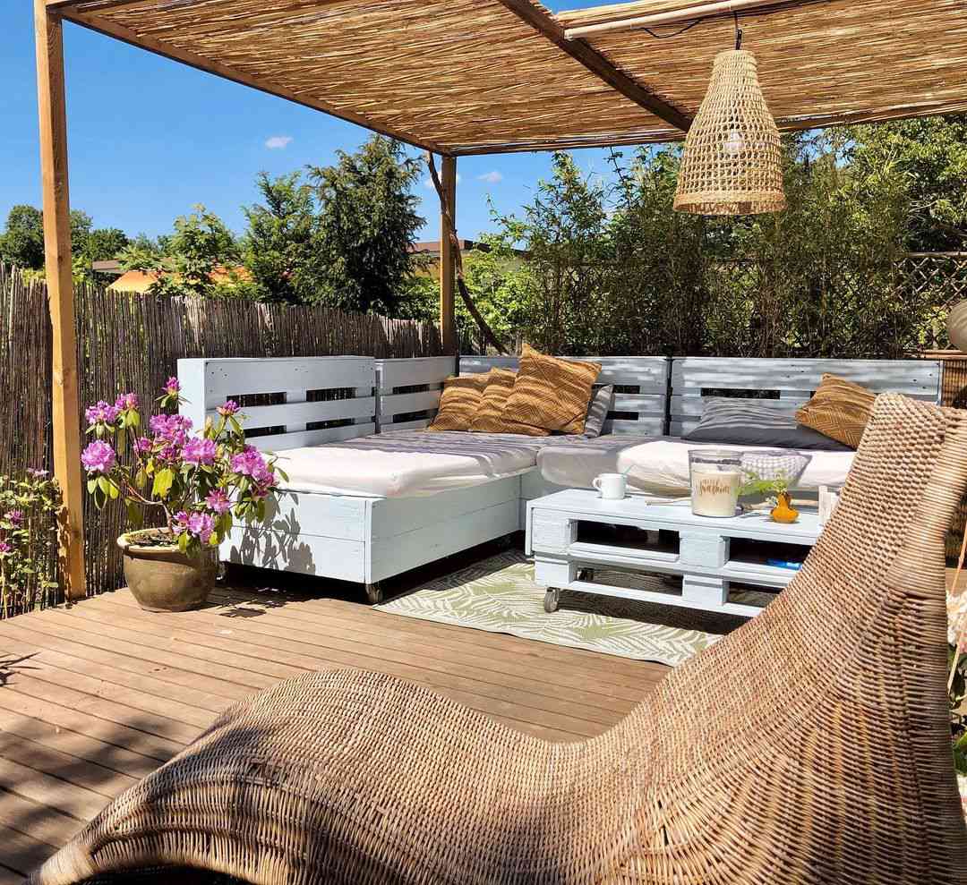 An outdoor living room with wood pallet furniture and a woven pendant light