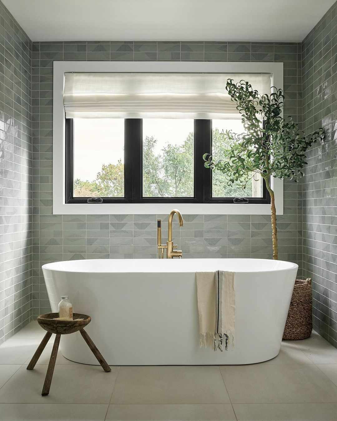 bathtub by window and fake plant in bathroom