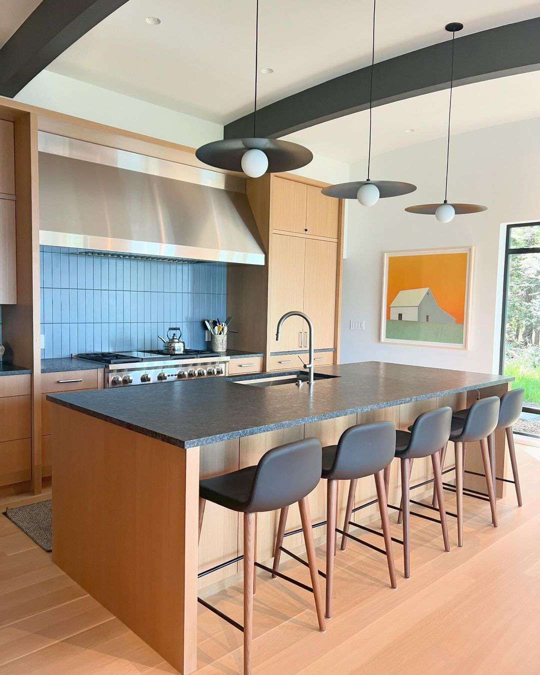 Moderne Küche mit leichten Holzkabinen, blauem Fliesenbacksplash und gelbe Scheunenkunst