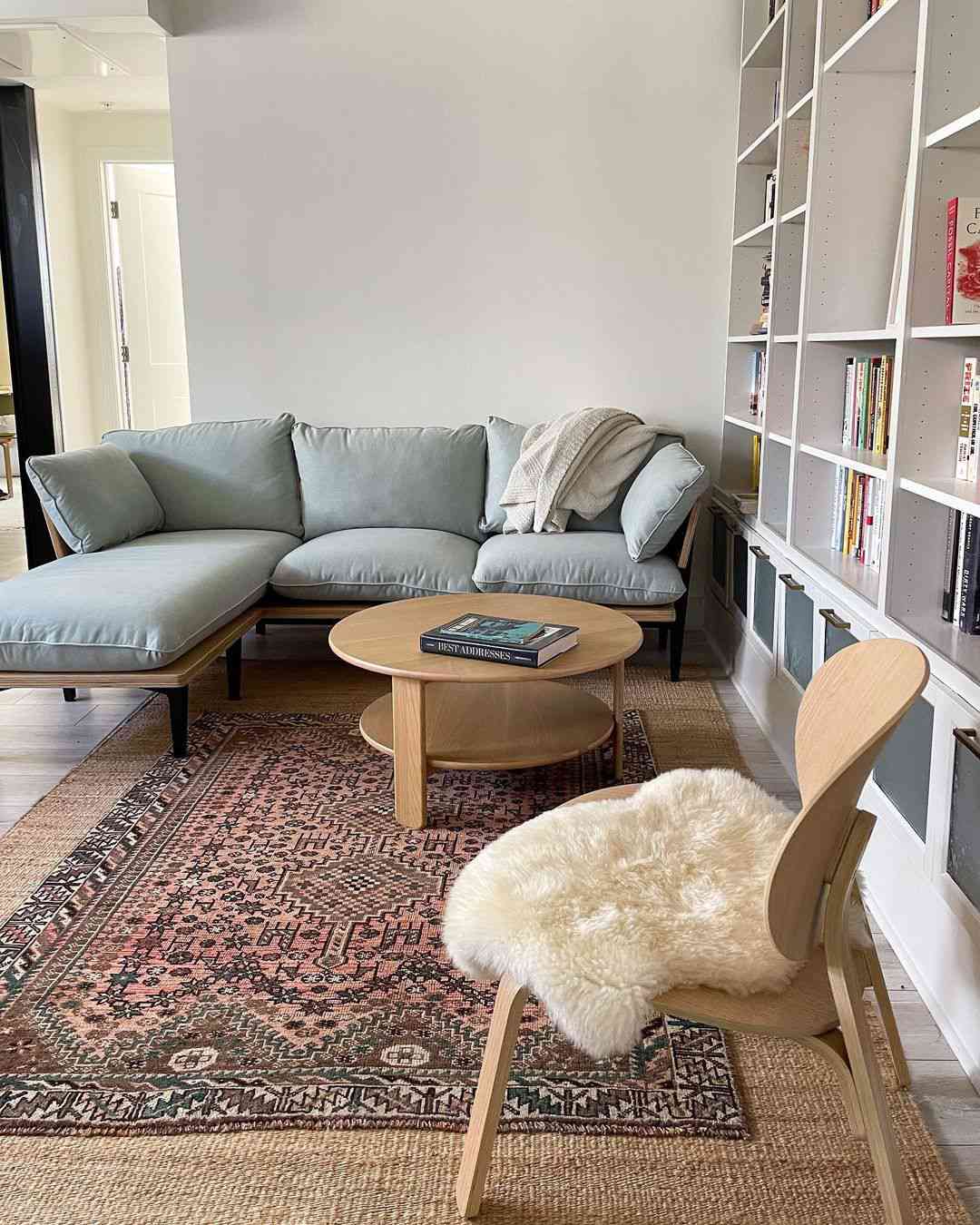 Designer lieben diesen Designtrend in diesem Jahr (und es ist tatsächlich erschwinglich) 2 Eklektisches Wohnzimmer mit Vintage -Teppich und weichem blauem Sofa.