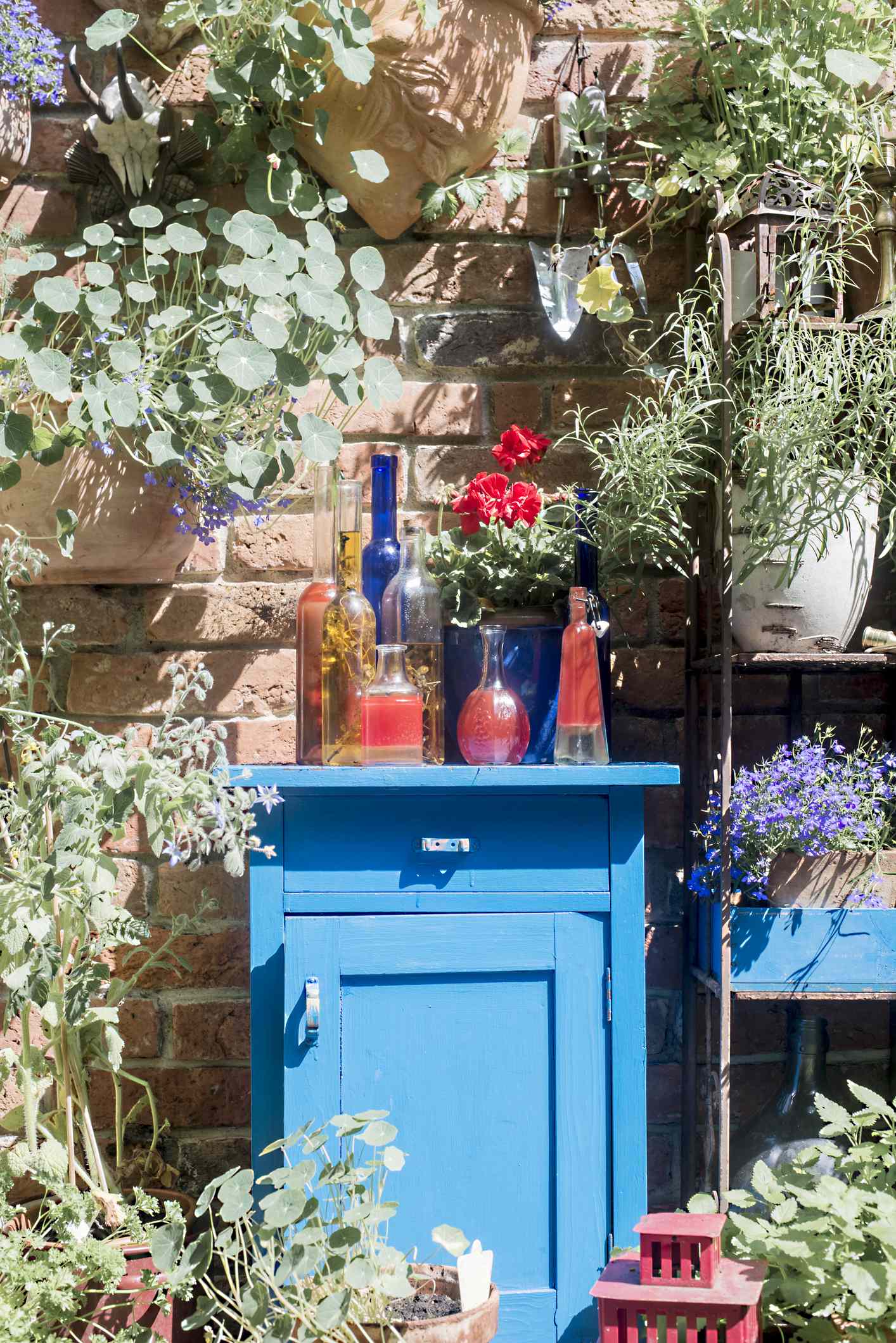 Blauer Schrank im Garten mit Glasflaschen