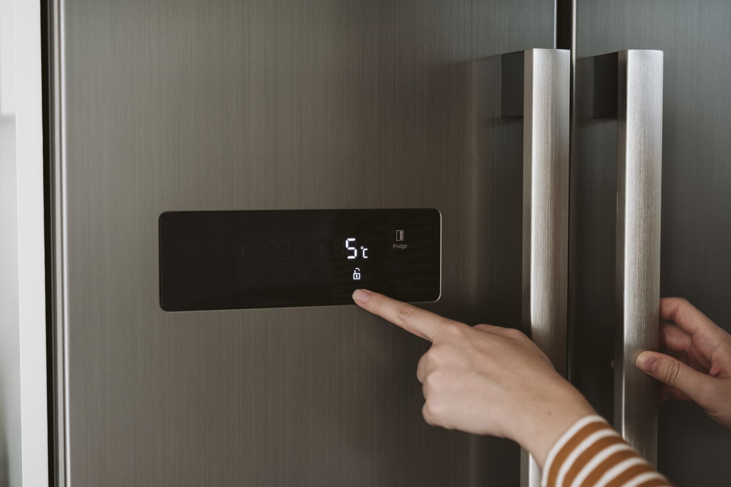 Nahaufnahme der Frau, die die Kühltemperatur im Kühlschrank einstellt