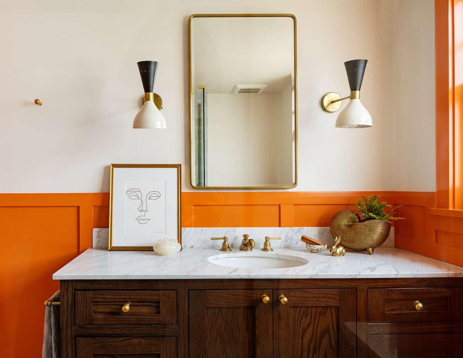 Retro -Badezimmer mit orangefarbenen Wainscotten und schwarz -weißer italienischer moderner Wandleuchter 