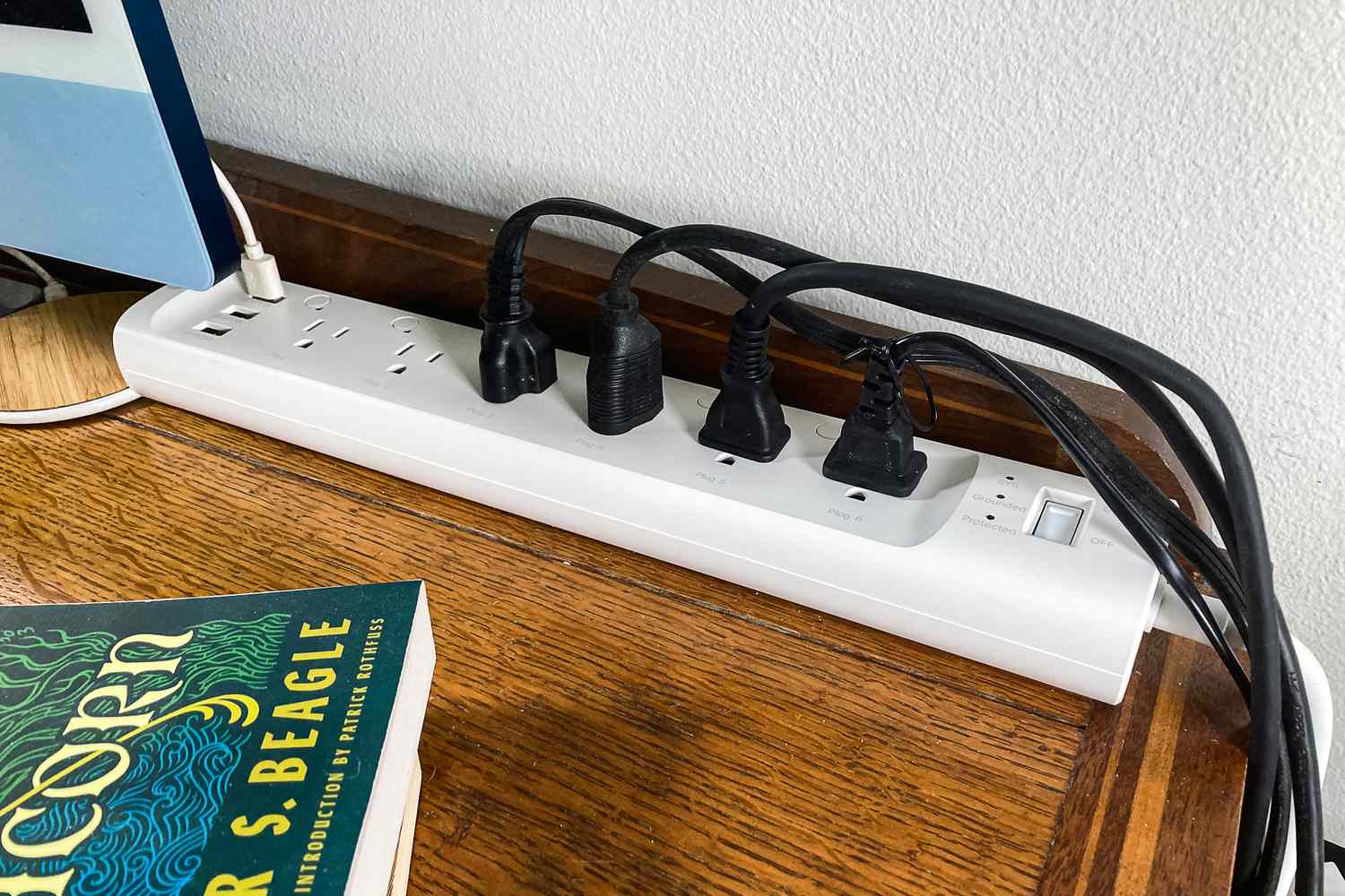 A Kasa Smart Power Strip with plugged-in cords on a desk