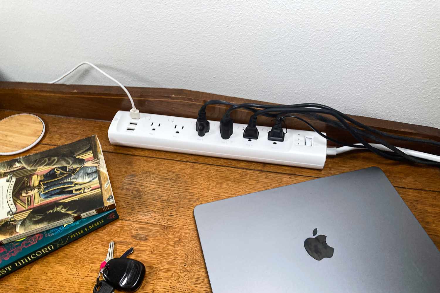 A desk with a Kasa Smart Power Strip, a laptop, a book, and keys