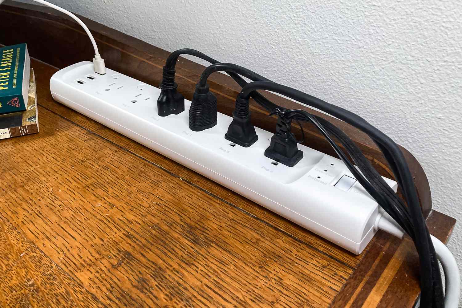 A Kasa Smart Power Strip with several plugs on a wooden surface next to books