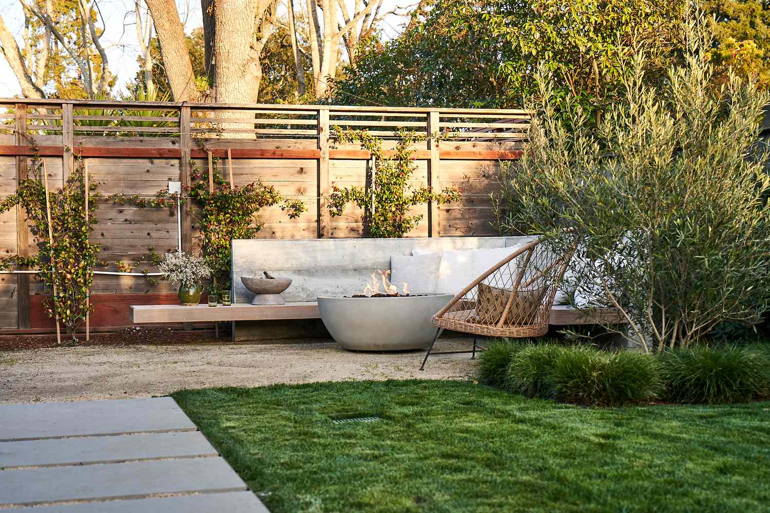 6 Backyard -Privatsphäre Korrekturen, die sich ohne den Preis luxuriös fühlen, sagen Designer, sagen Designer 8 Ruhiger Garten mit Betonfeuerschale und Kletterreben, die auf der Fenceline gepflanzt sind