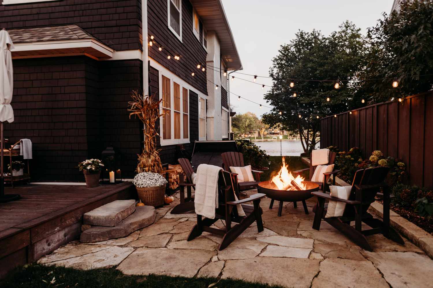 6 Backyard -Privatsphäre Korrekturen, die sich ohne den Preis luxuriös fühlen, sagen Designer, sagen Designer 12 Malerischer Seitenhof mit Flaggensteinen, Adirondak -Stühle und Saitenleuchten