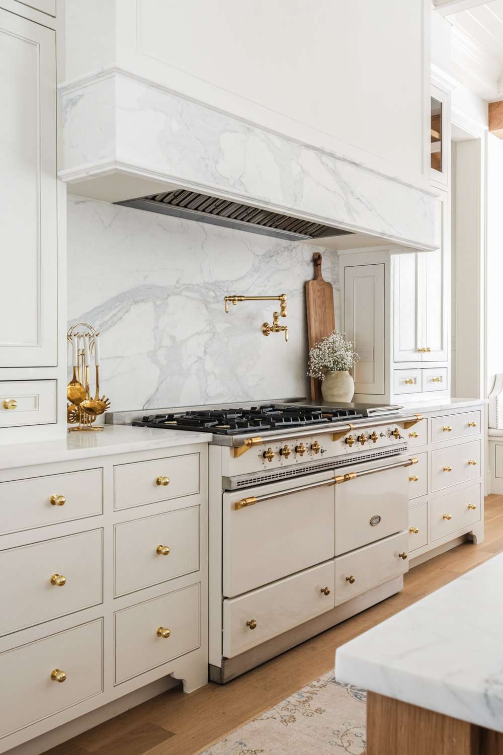 Elegante weiße Küche mit goldenen Schrankknöpfen.