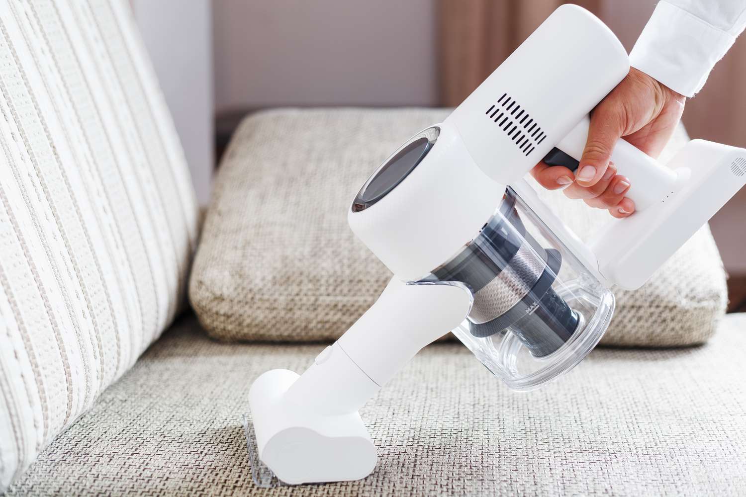 Person, die einen handgehaltenen Dampfreiniger verwendet, um ein gepolstertes Sofa zu reinigen