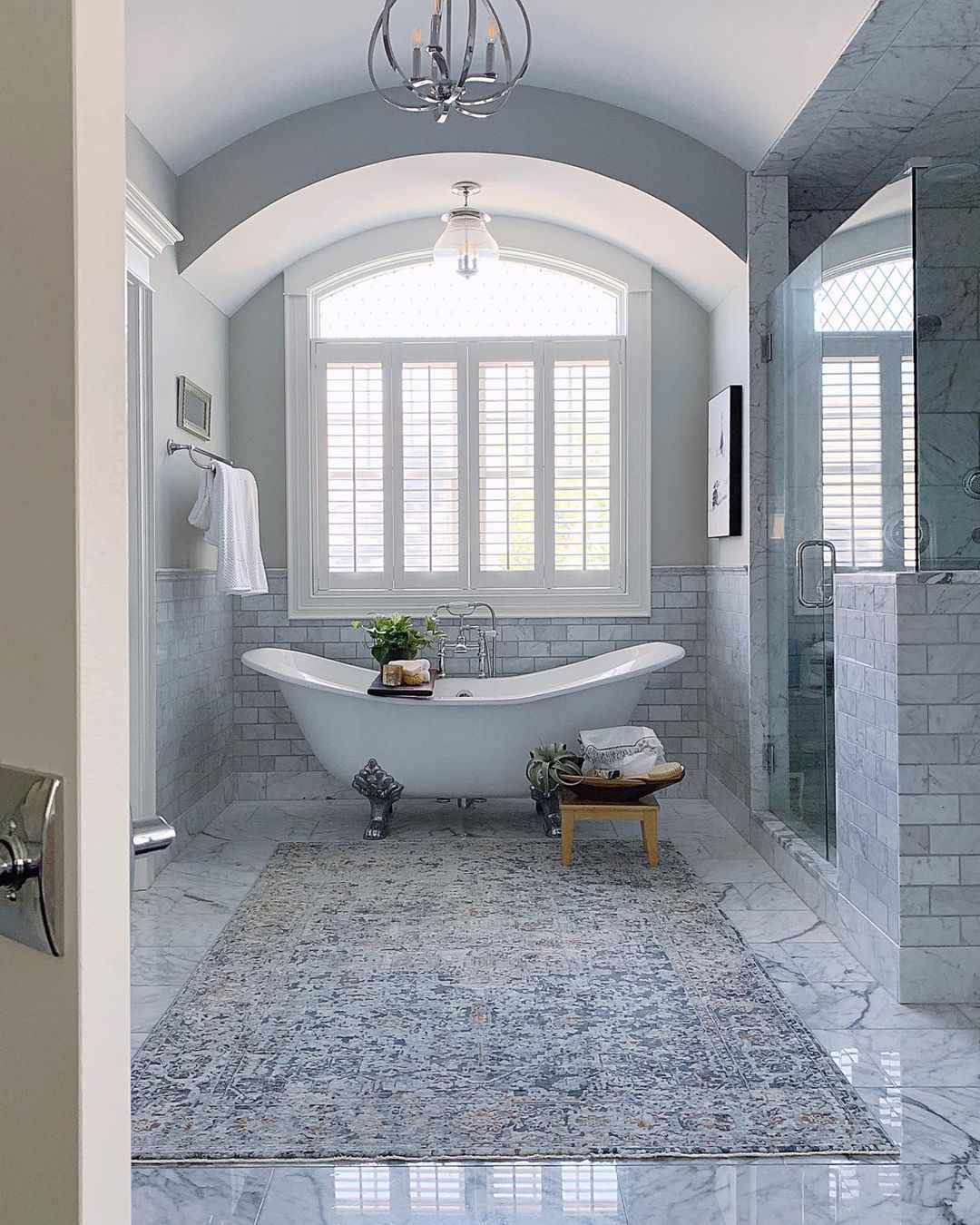 A large area rug in a luxurious bathroom with a freestanding bathtub