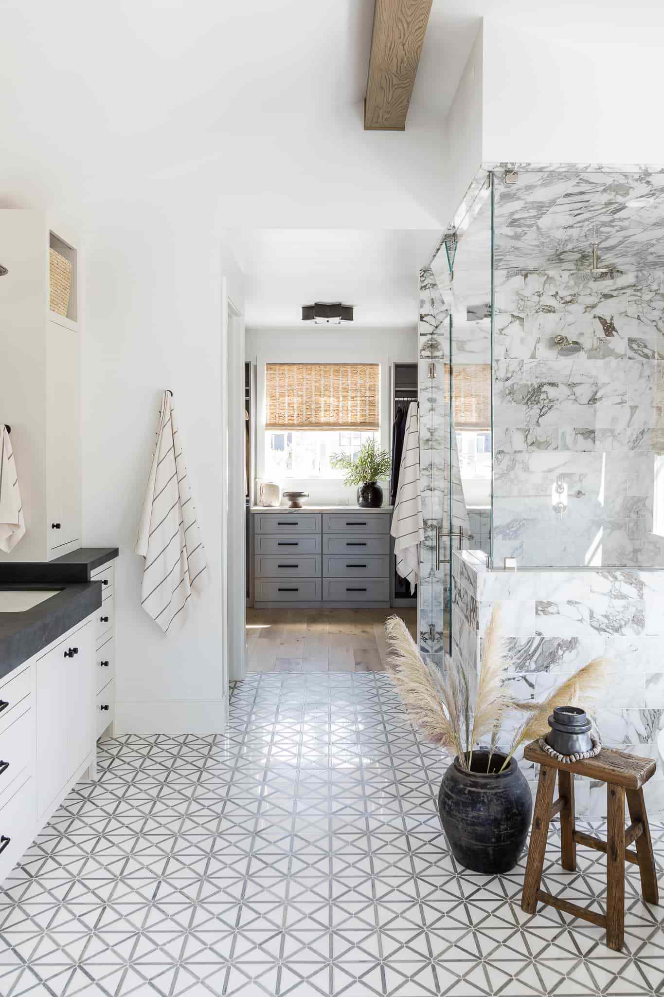 A bathroom with a marble shower and pampas grass decor