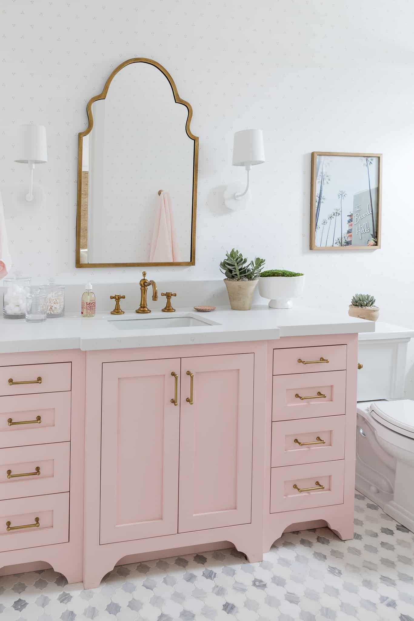 An ornate mirror and pink bathroom vanity