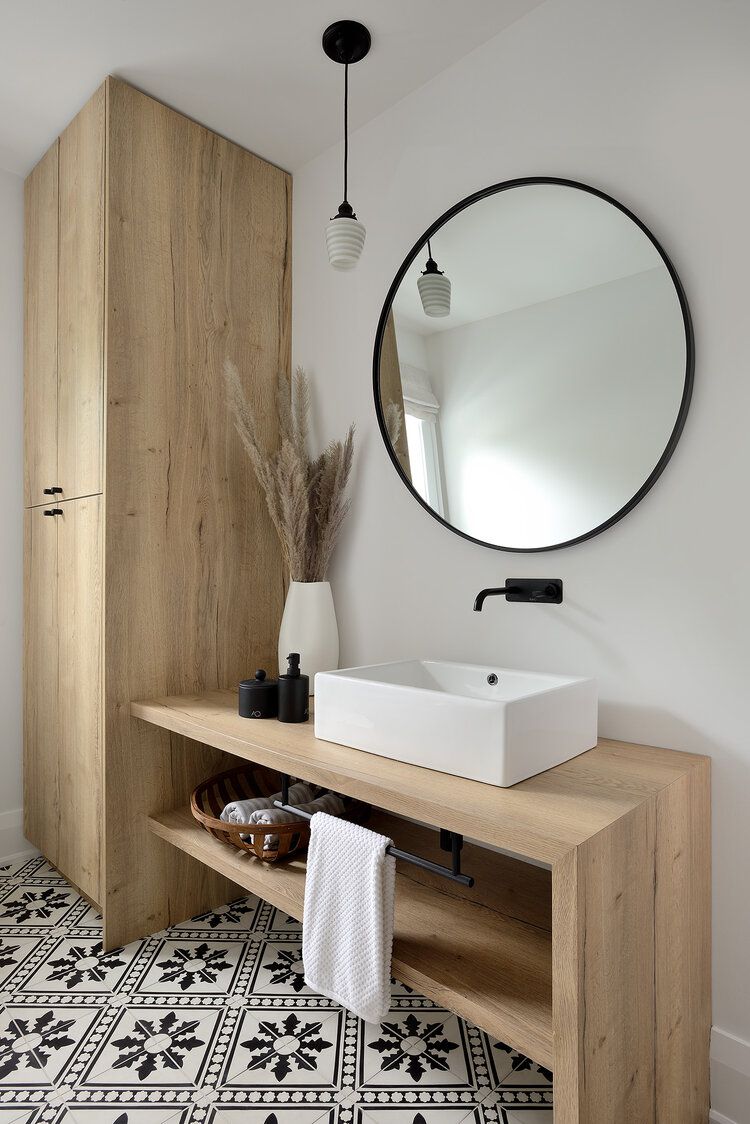 A neutral bathroom with a wood vanity and storage cabinet