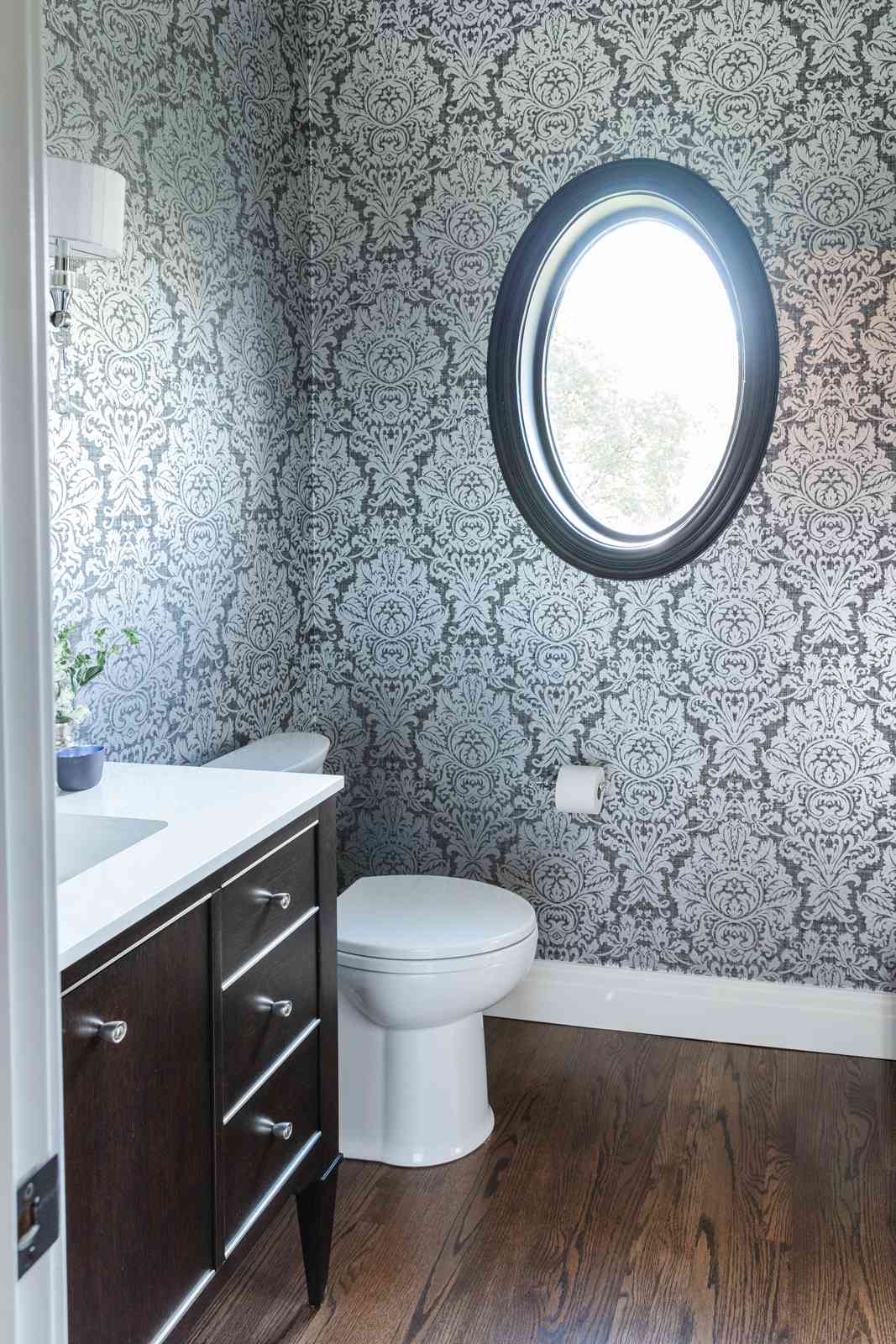 A small bathroom with damask wallpaper