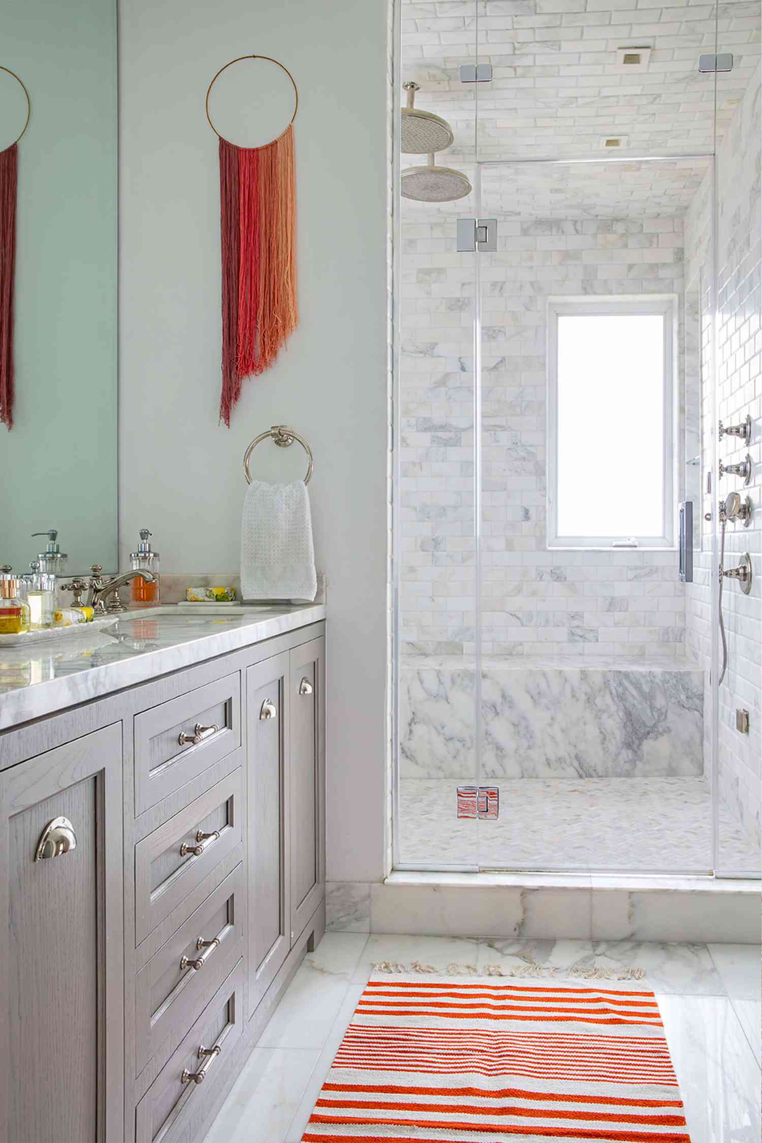A neutral bathroom with colorful hanging yarn art