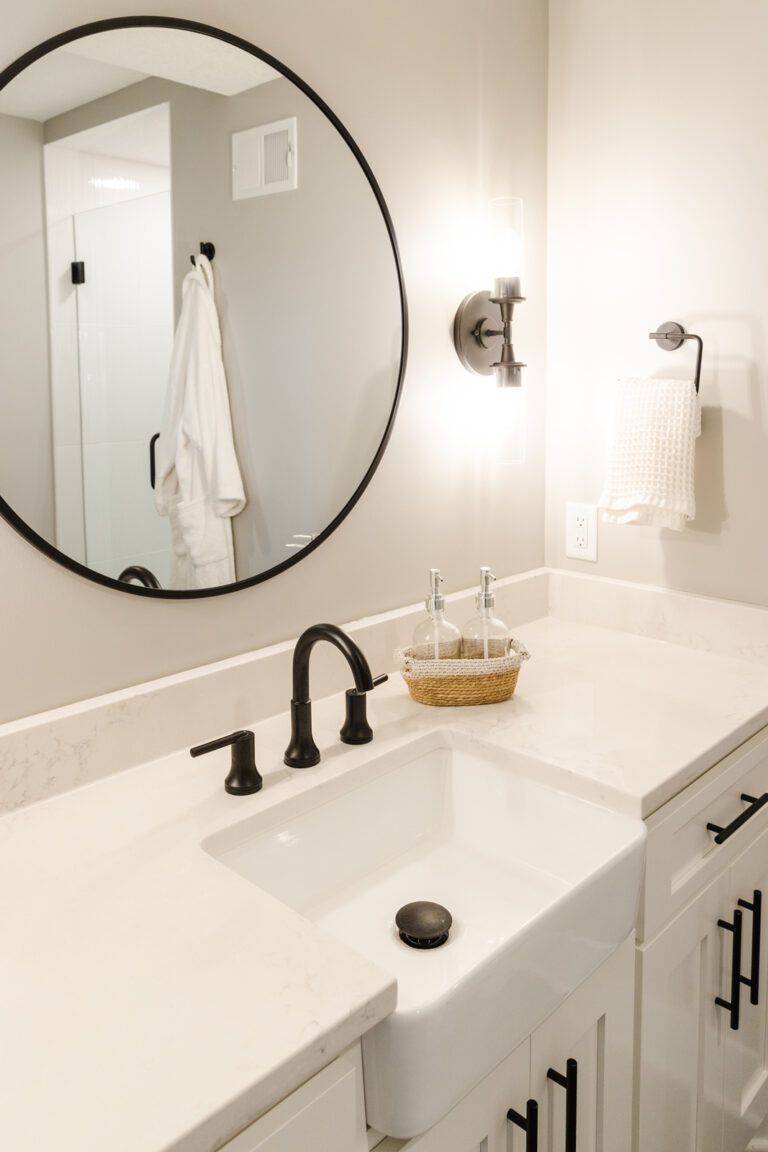 A bathroom with a round mirror and white countertop