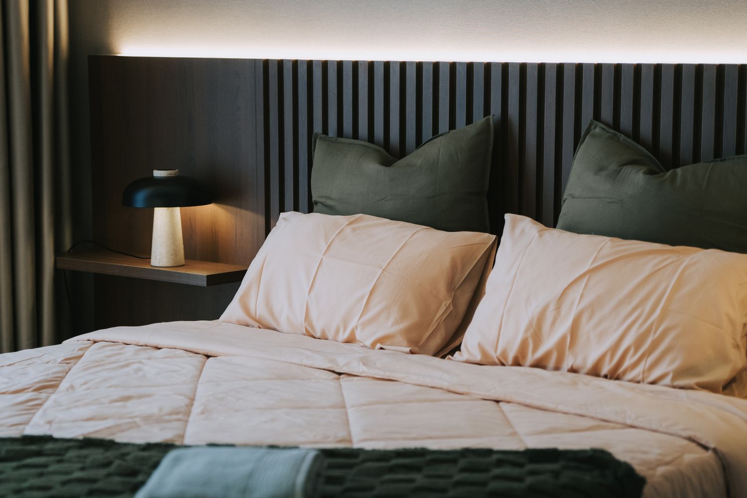 Large bed, white sheets, and rust-colored throw pillows and blanket. 