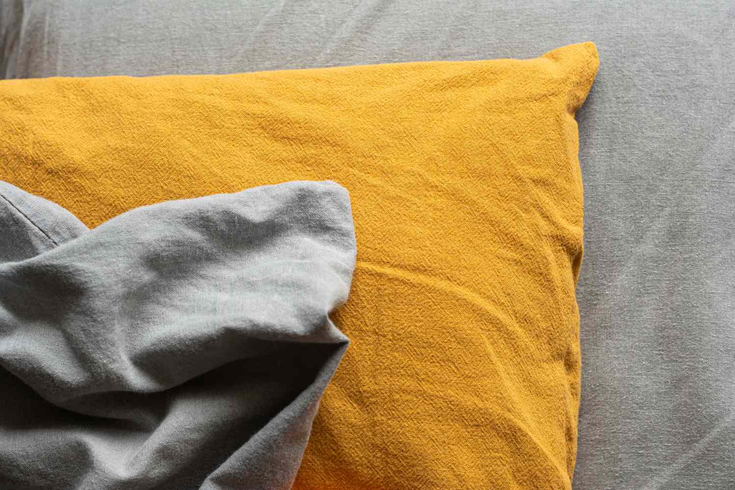 A textured pillowcase on a gray bedsheet.