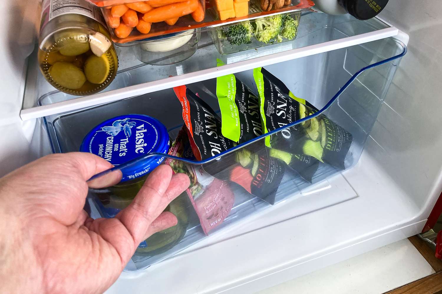 Hand opening a drawer inside the West Bend Mini Fridge containing various food items