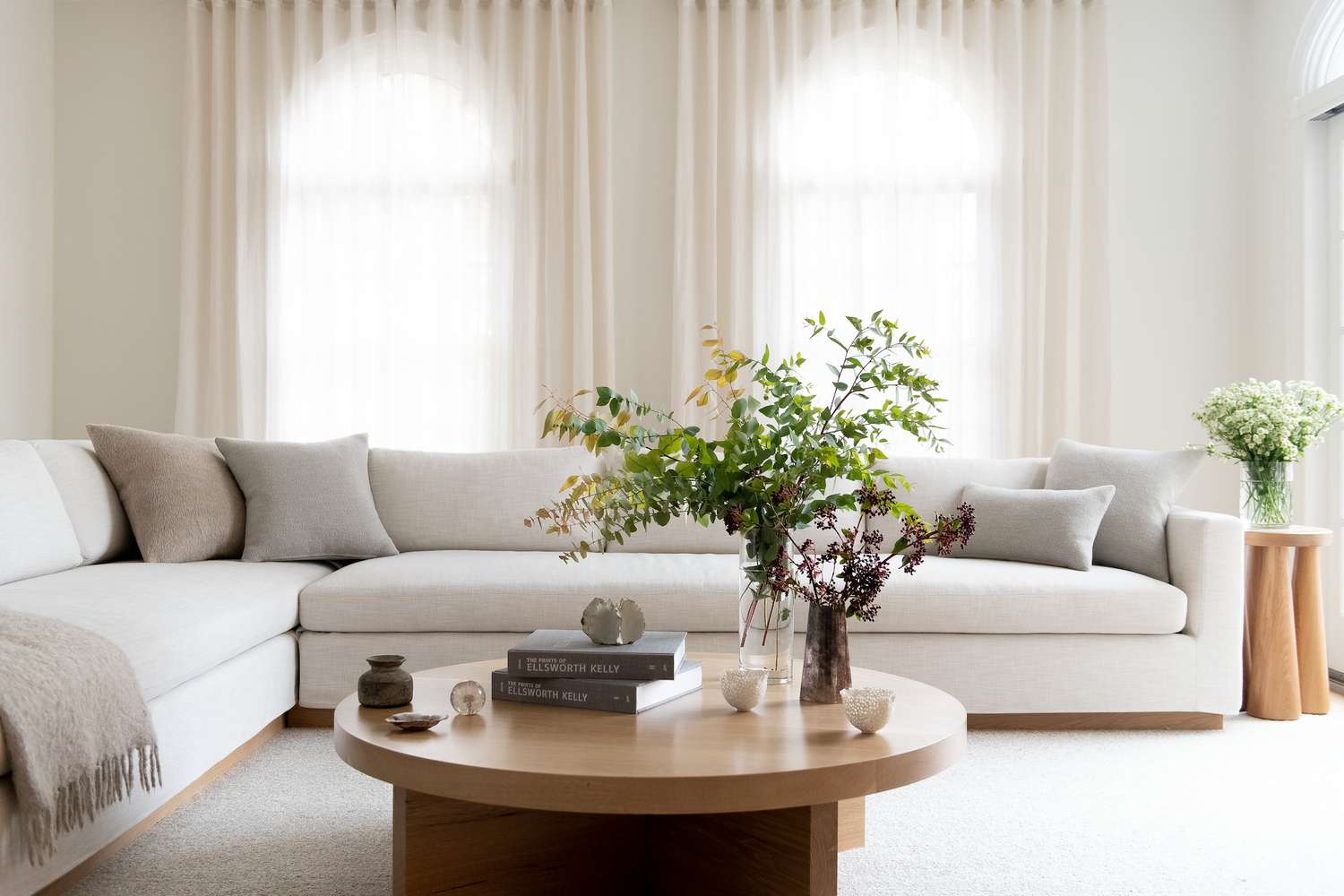 Weißes Wohnzimmer mit cremefarbener Couch und hölzernen Couchtisch