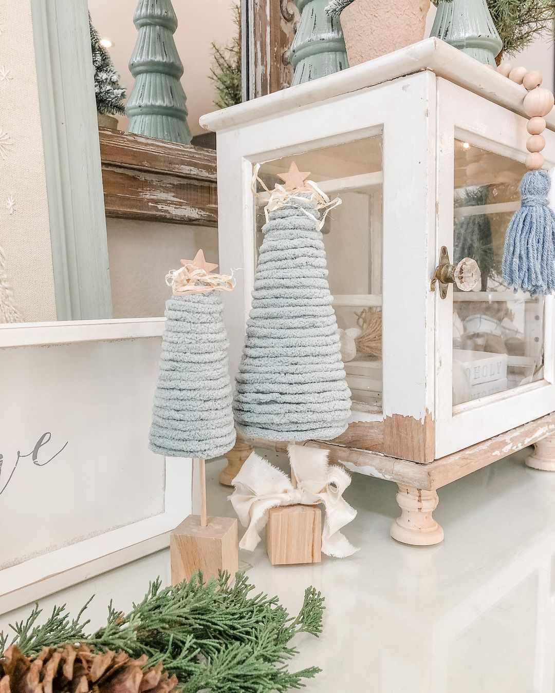 Two small wooden trees made from blue yarn
